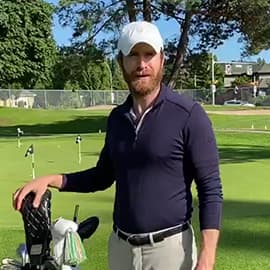 Man smiling on golf course with hand on golf bag.