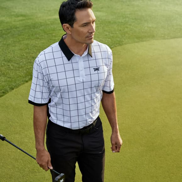 Man on a golf course in PXG apparel holding a club