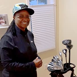 Woman smiling next to her golf bag.