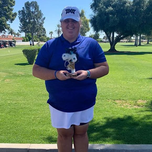 Haley Moor holding a trophy with a golf course in the background