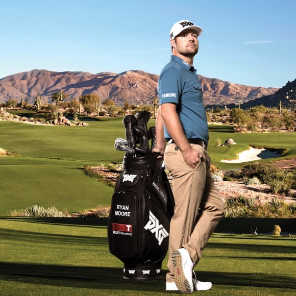 PGA Tour player Ryan Moore standing on golf course with hand resting on golf bag.