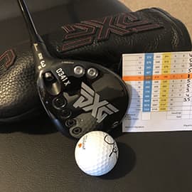 PXG Fairway Wood laying on headcover next to golf ball and golf scorecard.