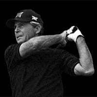 Headshot of Gary Player swinging a golf club on a black background