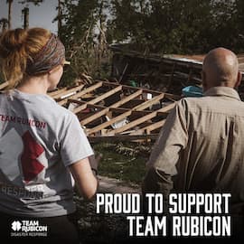 Members of Team Rubicon stand in front of wreckage