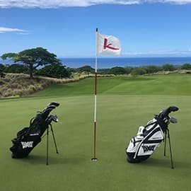 Two golf bags on a course with a hole/flag between