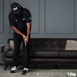 Man in PXG attire putting into a cup in a living room