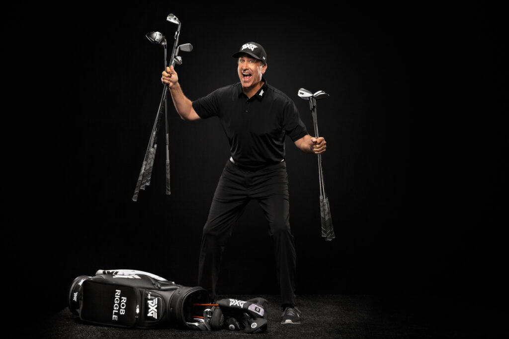 Rob Riggle, PXG Ambassador holding golf clubs in both Hands